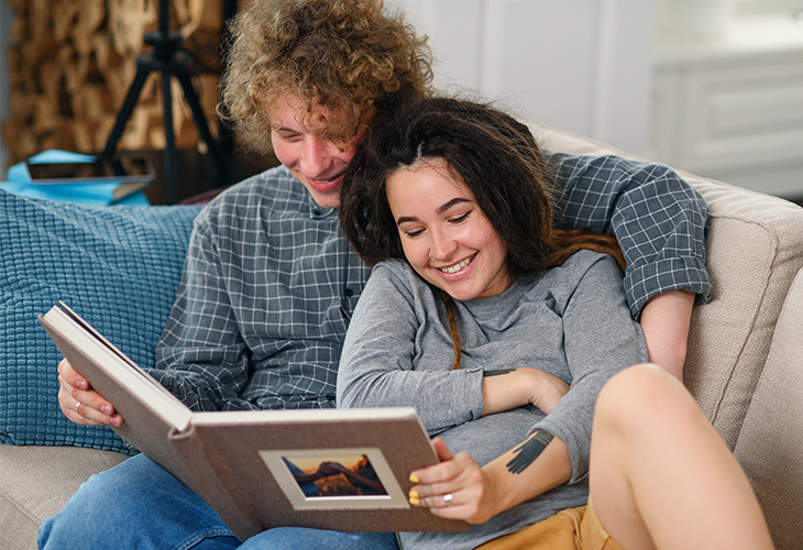Paar auf Couch liest Fotobuch